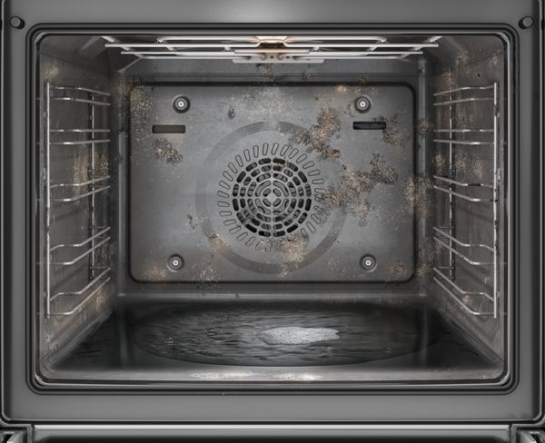 Interno di un forno sporco con incrostazioni e residui di cottura sulle pareti e sul fondo